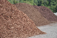 Hills of mulch with a gravel path and greenery in the background