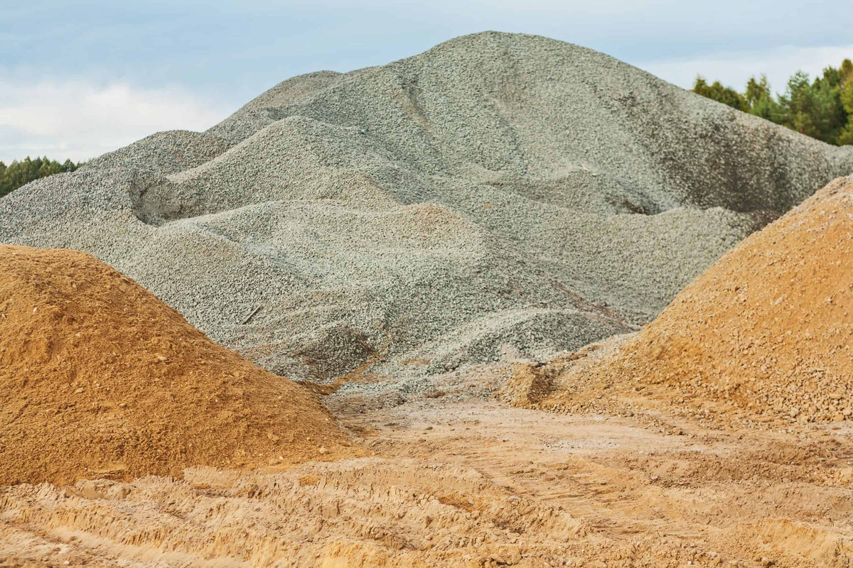 Hills of gravel and sand with a forest in the background